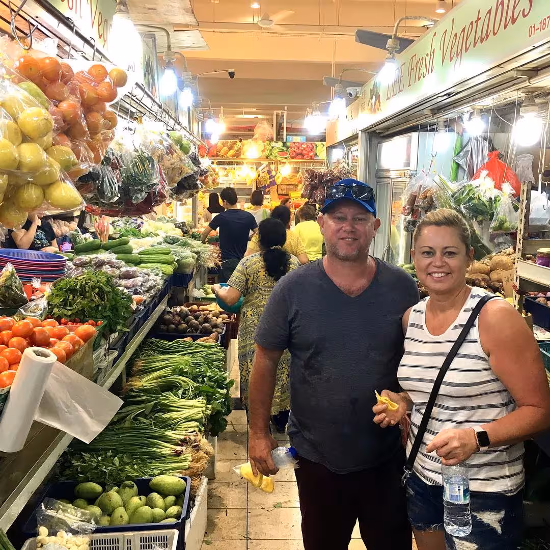 Couple exploring vibrant fresh produce market during ethnic neighborhood tour.