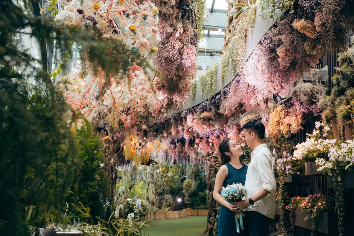 Couple smiles amidst vibrant floral backdrop in a Singapore garden, ideal for a professional photoshoot experience.