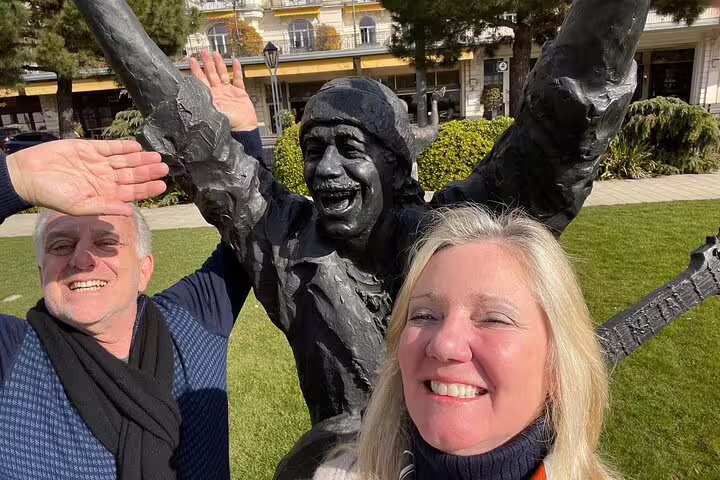 Couple posing with Freddie Mercury statue in Montreux on a self-guided scavenger hunt walking tour by the lake