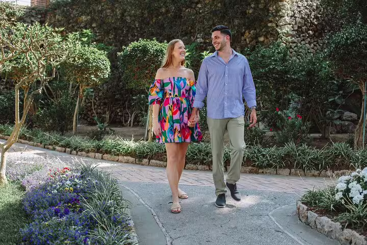 Couple walking hand in hand through a lush garden during a private photoshoot in Naples.