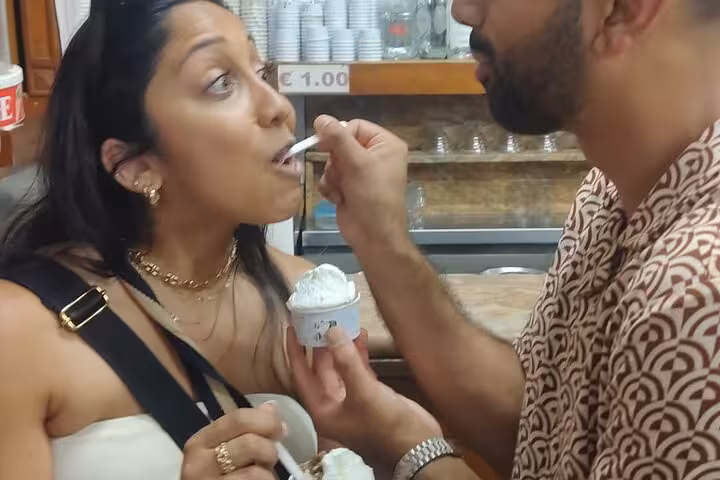 Couple enjoying gelato at a local Roman gelateria during a Vespa tour of Rome's highlights.