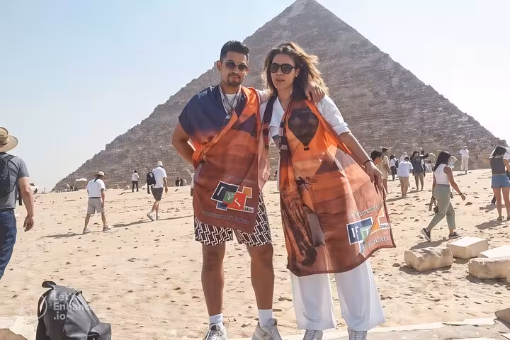 Couple posing at Giza Great Pyramid on Hurghada to Cairo legacy tour, with desert backdrop and visitors