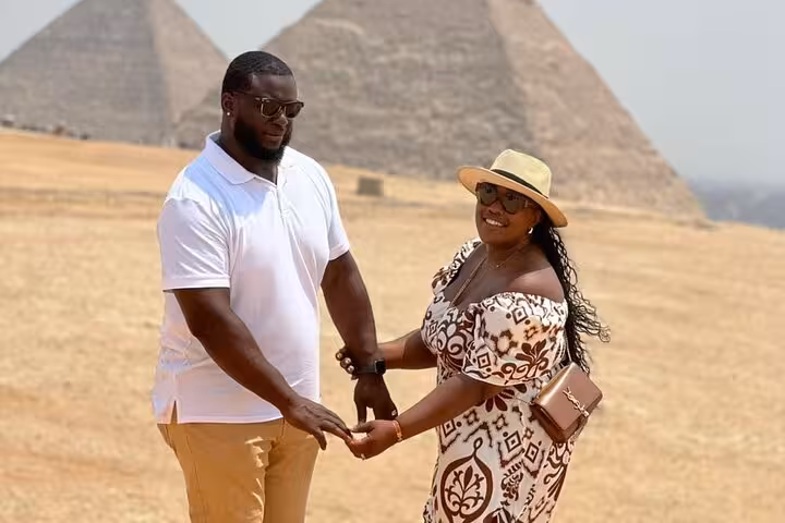 Couple holding hands at the Giza Pyramids during a private Cairo tour, guided visit with photo opportunities
