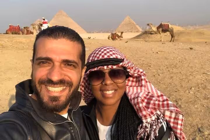 Couple selfie at Giza Pyramids during private tour with camel ride, Sahara desert backdrop and sunset light