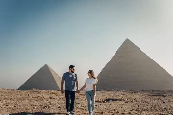 Couple walking by Giza Pyramids on VIP all-inclusive tour, private guide experience in Cairo desert