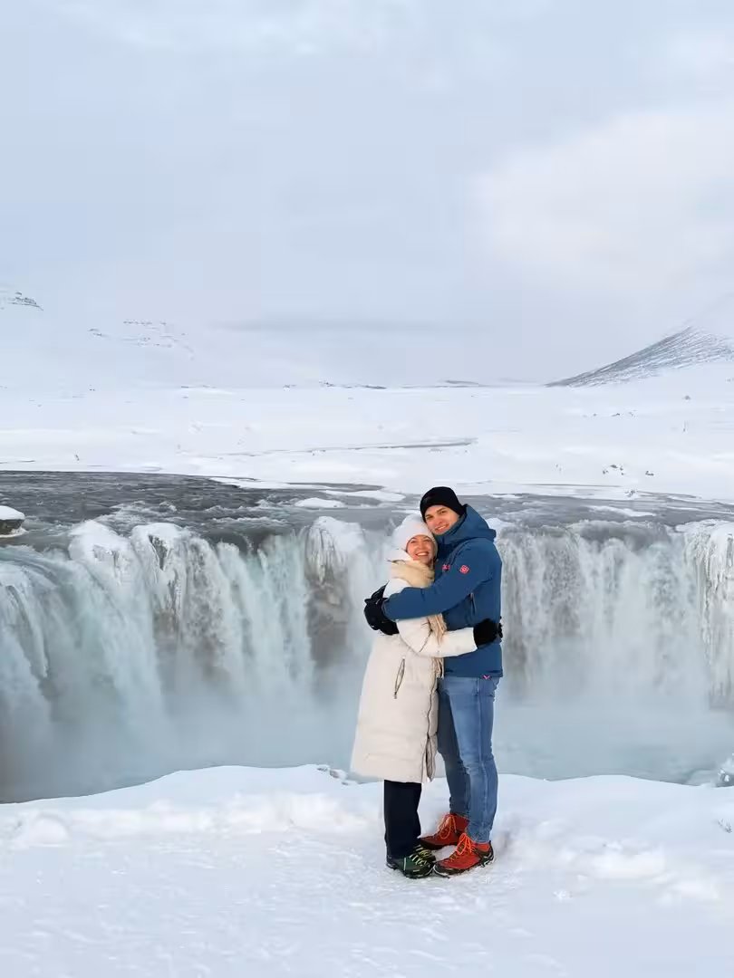 Couple hugging at Goðafoss Waterfall in winter on a private Sacred Iceland tour with Christmas dreams and cacao ceremony