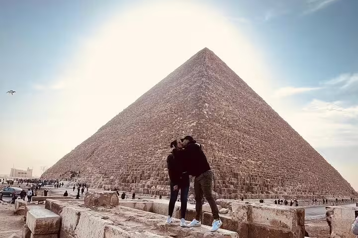 Couple posing by the Great Pyramid of Giza on a private Sakkara Pyramids desert safari tour from El Sokhna Port