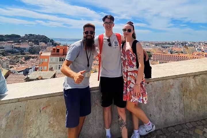 Couple with guide at Lisbon viewpoint on a 4-hour private tuk tuk tour, panoramic city skyline