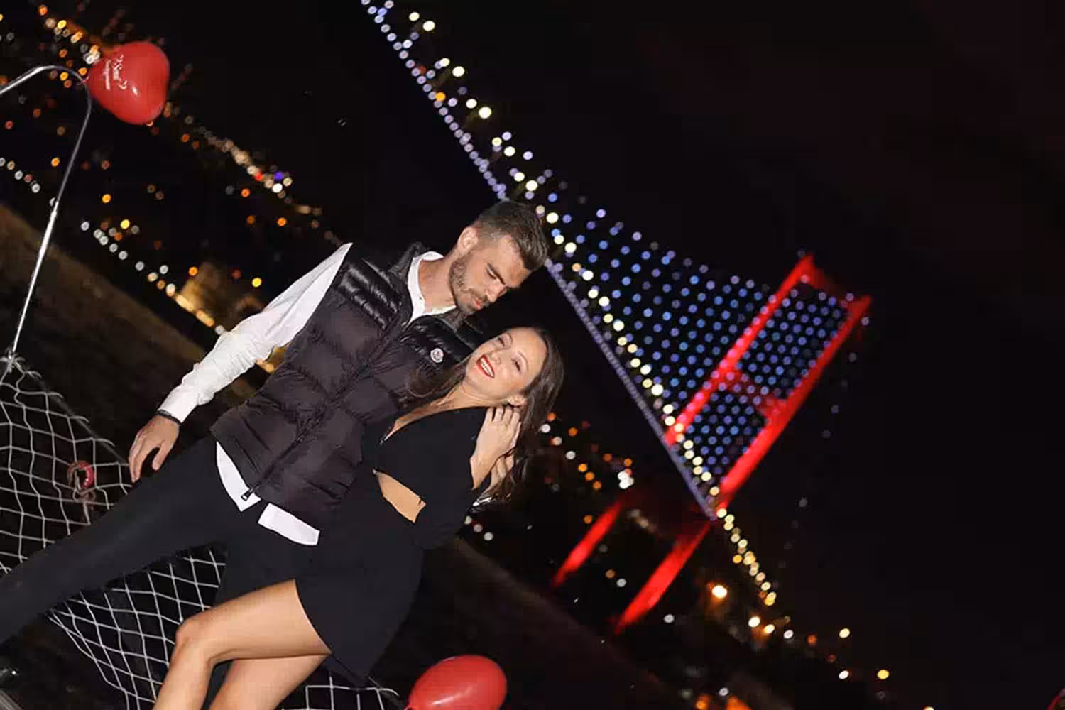 Couple posing with heart balloons on a private Bosphorus yacht at night, romantic marriage proposal setup