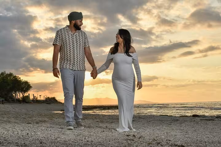 Couple holding hands on Ammoudara beach at sunset during private photoshoot experience.