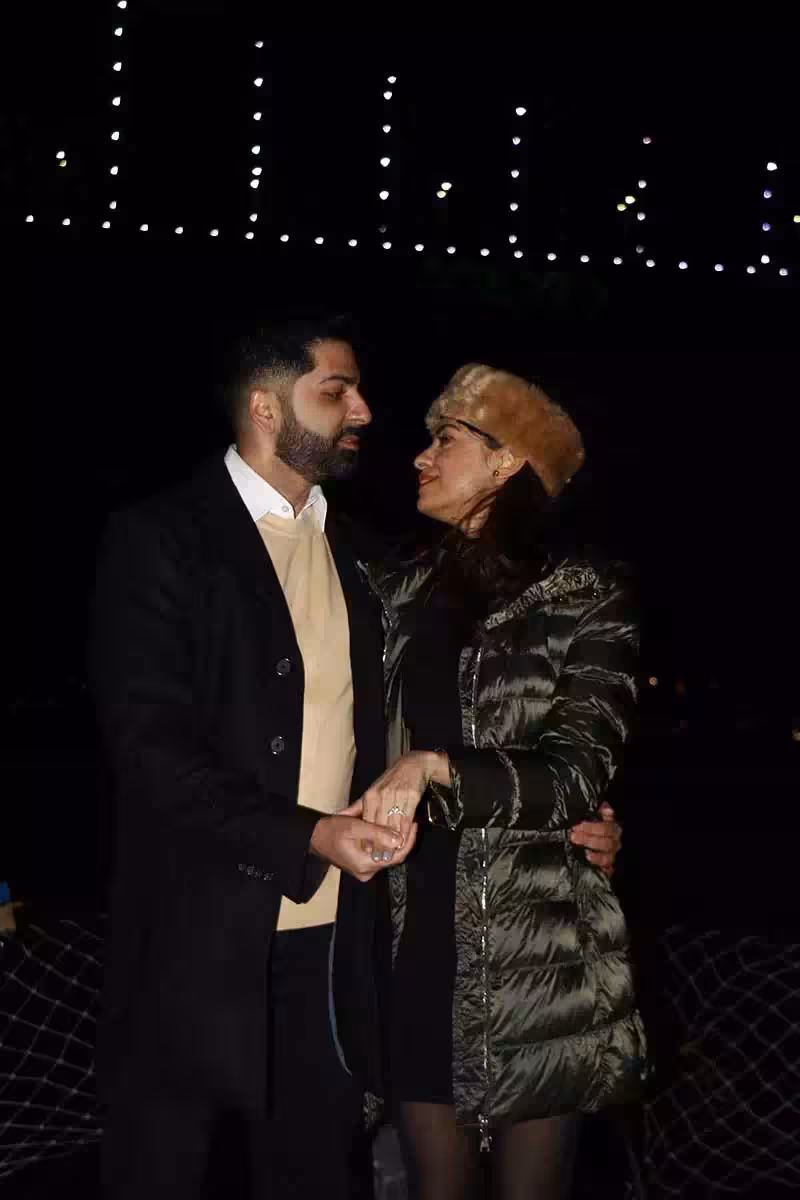 Couple holding hands under string lights at night, romantic marriage proposal experience with photographer session