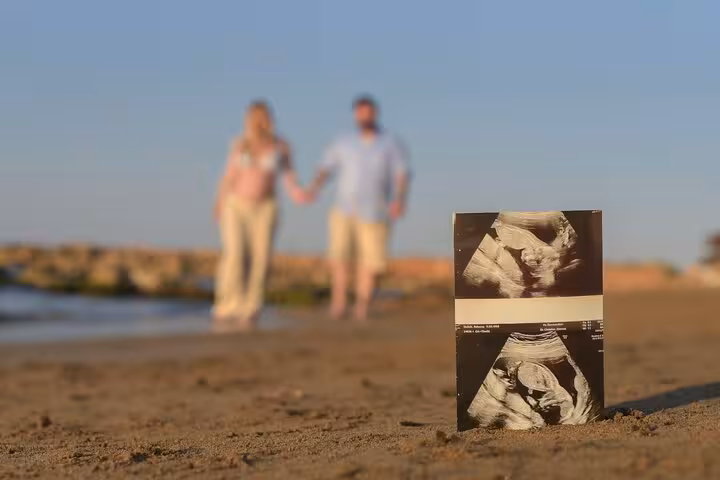 Couple holding hands with ultrasound photo on Gouves beach, capturing a memorable private photoshoot moment.