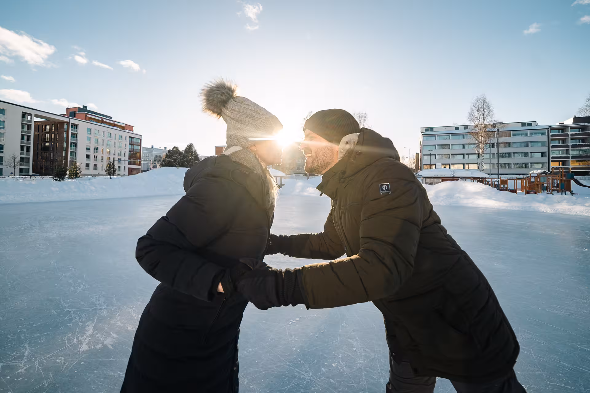 Couple playfully embracing on an ice rink under the winter sun during a private photo session in Rovaniemi.