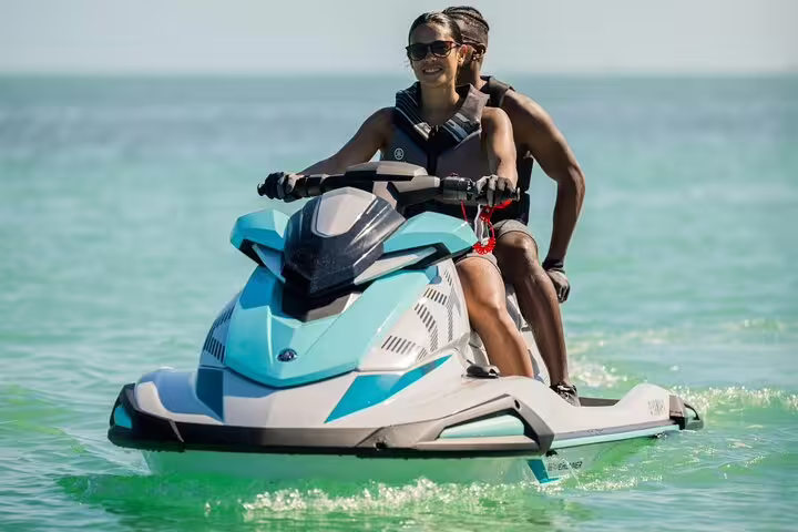 Couple riding a jet ski on Ibiza’s turquoise sea during a guided Cala Comte jet ski tour