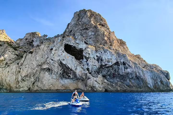 Couple on jet ski near Es Vedrà cliffs on a San Antonio Ibiza guided jet ski excursion over turquoise water