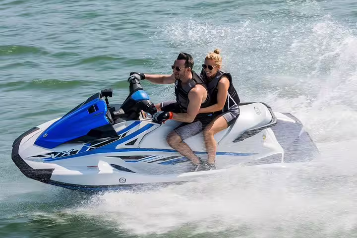 Couple riding a jet ski at speed on Ibiza sea, San Antonio departure on Es Vedrá jet ski tour