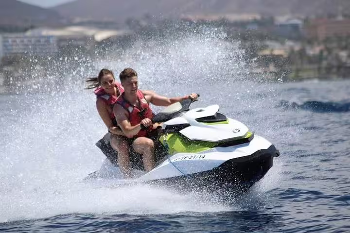 Couple enjoying an exhilarating ride on a jet ski amidst splashing waves during a 2-hour jet ski safari tour.