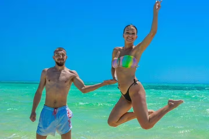Couple jumping by crystal-clear Red Sea at White Island, private VIP boat snorkeling tour to Ras Mohamed