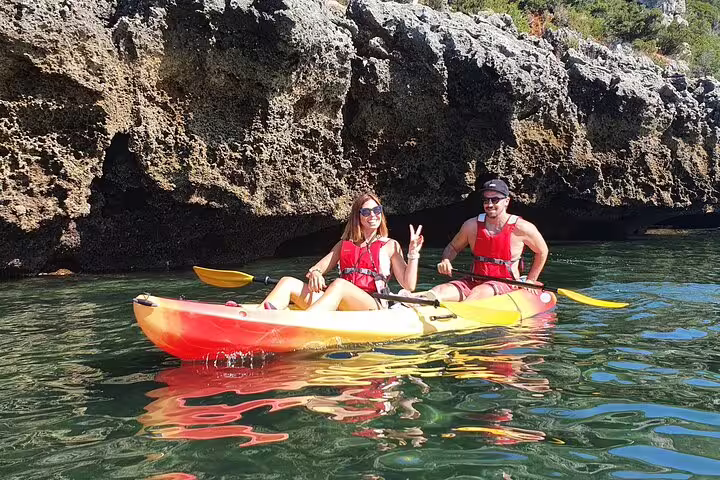 Couple enjoying a kayak adventure near rocky cliffs in Lisbon, perfect for snorkeling and exploring Portugal's stunning coastline.