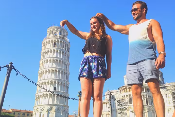 Couple posing playfully with the Leaning Tower of Pisa during a sunny day trip from Florence.