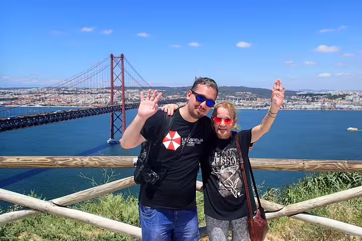 Couple enjoying scenic views of Lisbon's 25 de Abril Bridge during a South Sights & Wine tour, perfect for travelers.