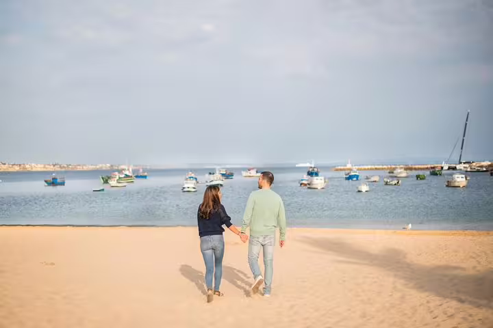 Couple walking on Lisbon beach by calm harbor boats during private vacation photographer photo shoot