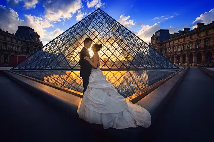 Couple at the Louvre Pyramid at sunset, perfect photo stop on a Paris Louvre visit with private guide option
