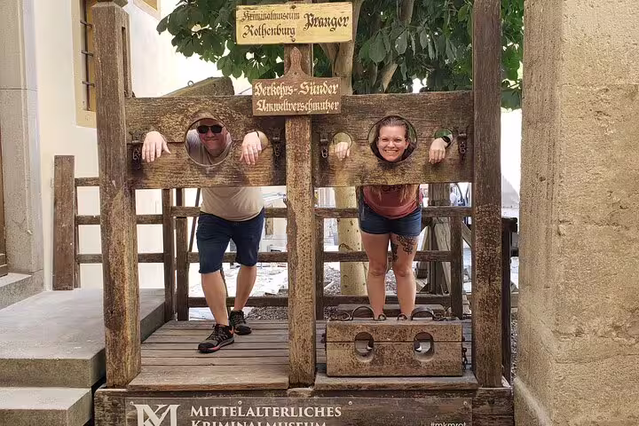 Couple posing in medieval stocks in Rothenburg, fun photo stop on a self-guided scavenger hunt sights tour