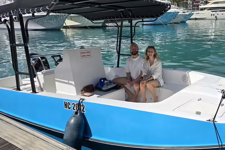 Couple sitting on a blue motorboat ready for a private snorkeling and fish feeding day trip in crystal clear waters.