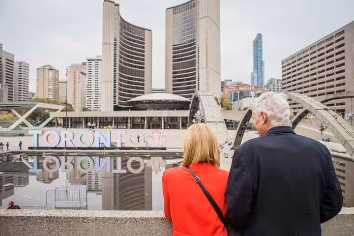 Couple at Nathan Phillips Square with Toronto sign, private travel photographer tour capturing city hall skyline