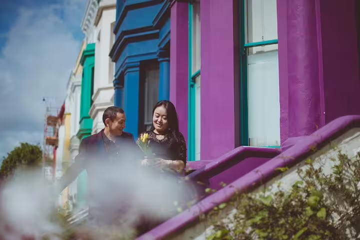 Couple smiling on vibrant Notting Hill steps in London, capturing the essence of a personal travel photography tour.