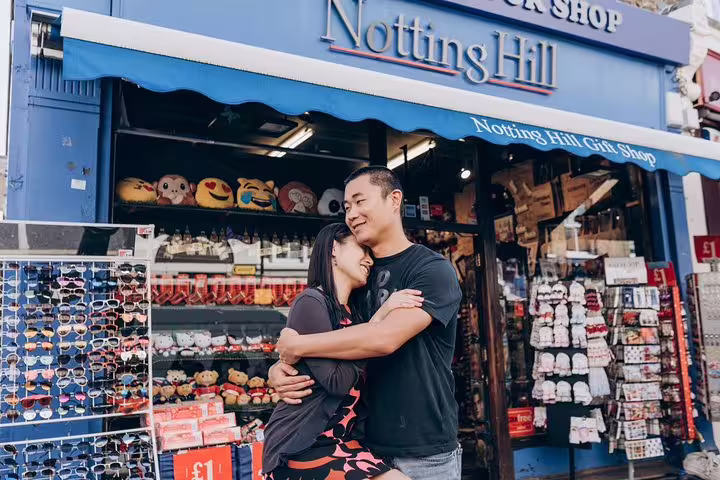 Couple embraces outside Notting Hill gift shop on personalized travel photographer tour in London.