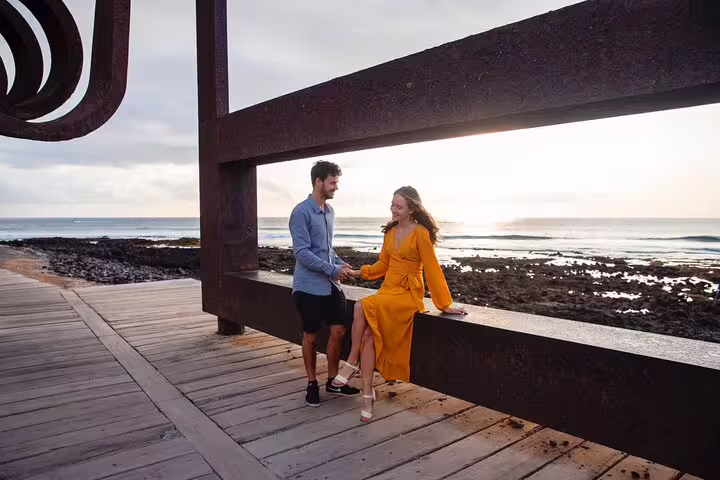 Couple posing by oceanfront sculpture on Tenerife boardwalk during a private photoshoot with professional photographer