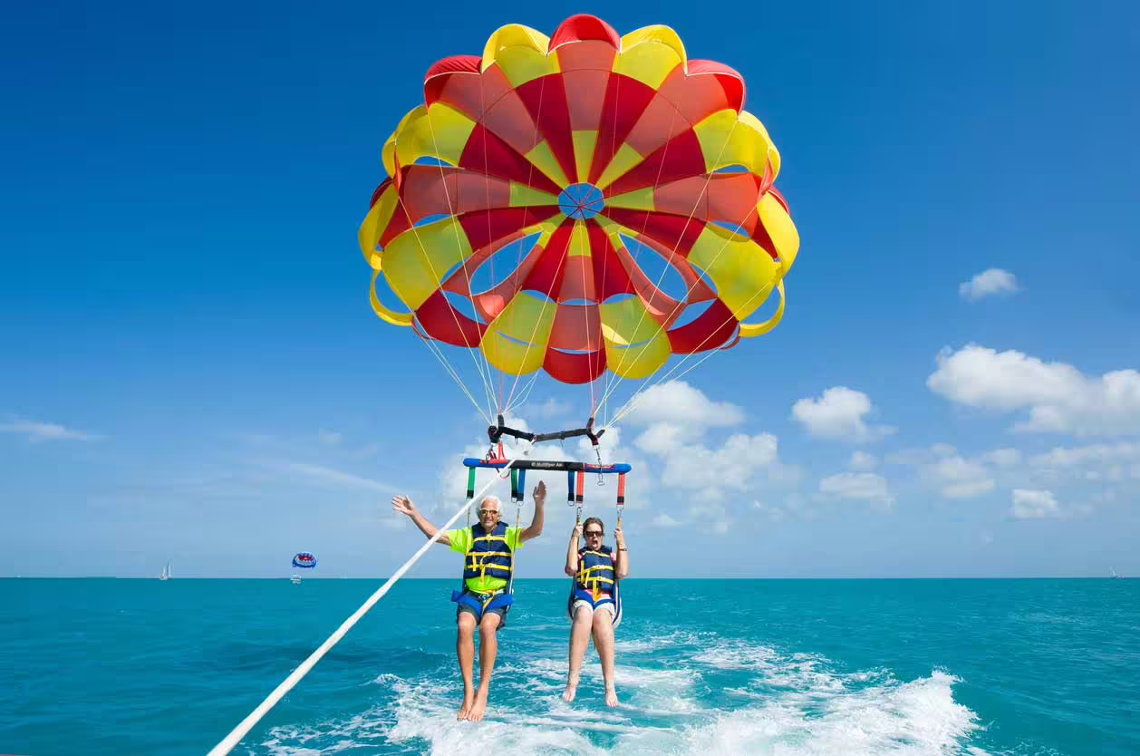 Couple parasailing in Hurghada above the Red Sea, colorful canopy and clear sky on an exciting watersports tour