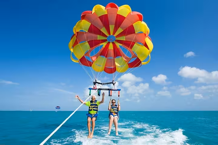 Couple parasailing over the Red Sea in Sharm El Sheikh with private transfer, colorful canopy and clear sky