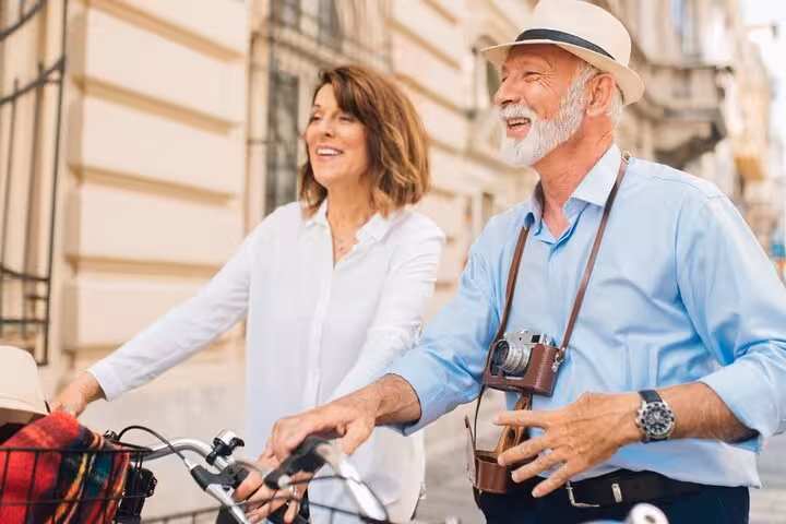 Smiling couple with bicycles on Paris street, ideal for a Seine bike tour with optional Louvre entry