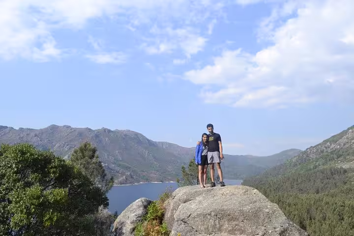 Couple standing on a rock with panoramic views of mountains and lake in Peneda Geres National Park.