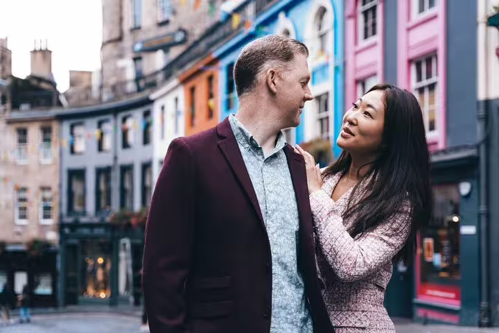 Couple enjoying a private photoshoot with colorful Victoria Street in Edinburgh as a backdrop.