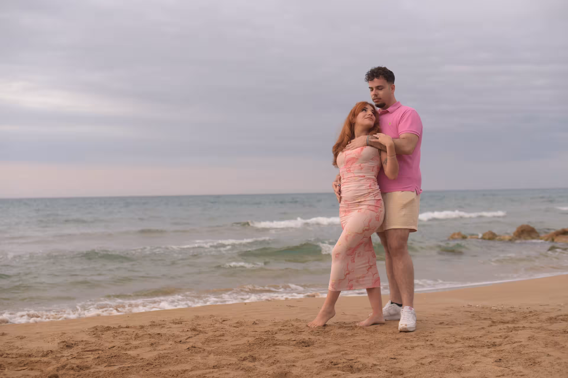 Couple poses lovingly on Heraklion Venetian Port beach, showcasing romance by the serene sea backdrop.