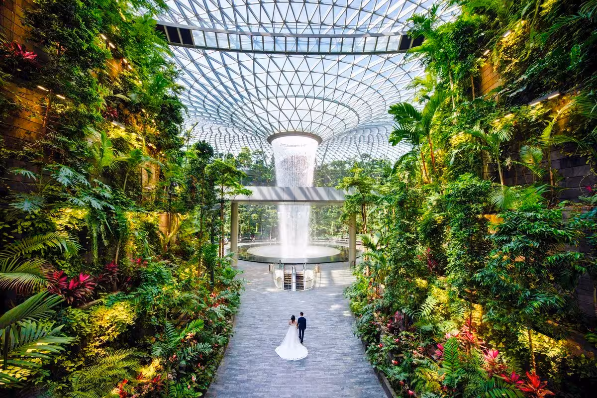 Couple walks through lush greenery at Jewel Changi Airport, perfect for a private photoshoot in Singapore.