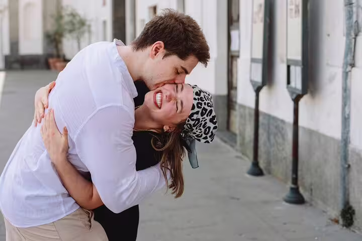 Couple embracing joyfully during a sunny private photoshoot in charming Naples street.