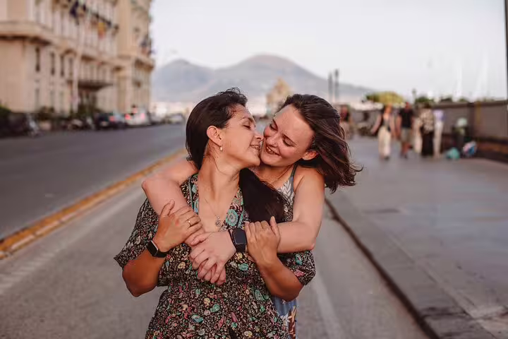 Happy couple embracing with Mount Vesuvius in the background during a photoshoot in Naples.