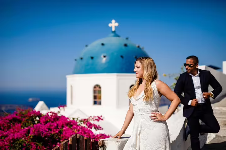 Couple enjoying a photoshoot with the iconic blue domes of Santorini, Greece as a stunning backdrop.