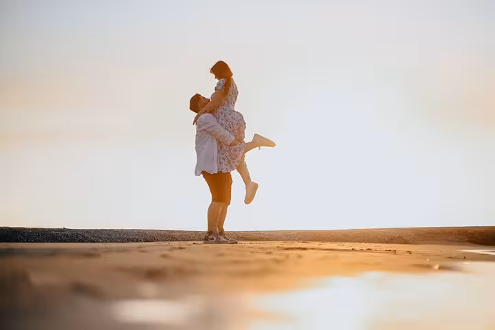 Joyful couple in a playful lift on a Gouves beach at sunset, perfect for a memorable photoshoot experience.