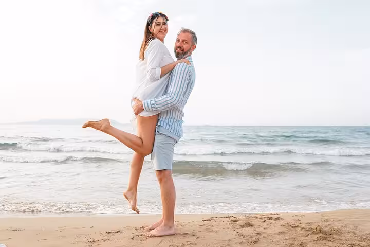 Couple enjoys a playful moment on sandy Heraklion beach, capturing love and joy during a private photoshoot.