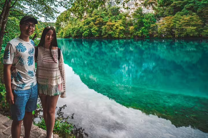 Couple posing by crystal-clear turquoise lake on a private Plitvice Lakes tour in Croatia national park