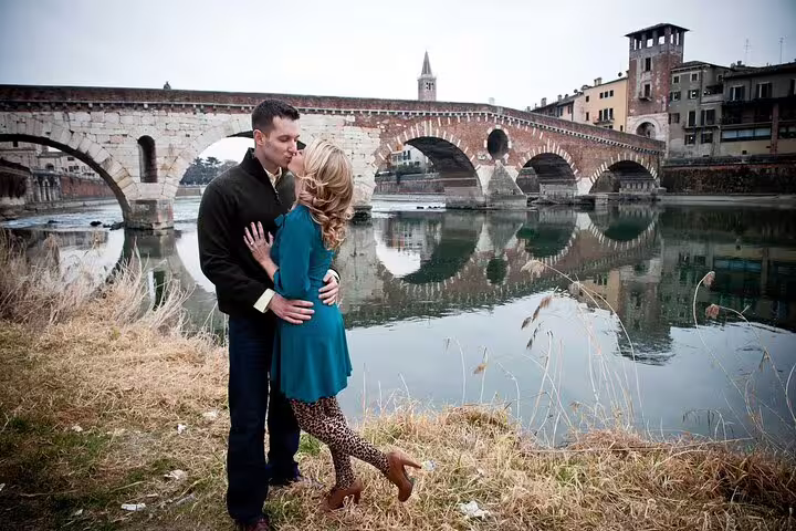 Couple embracing by the historic Ponte Pietra in Verona, highlighting a professional photoshoot tour.
