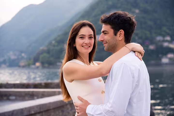 Couple portrait by Lake Como waterfront with mountains, private travel photographer tour in Italy