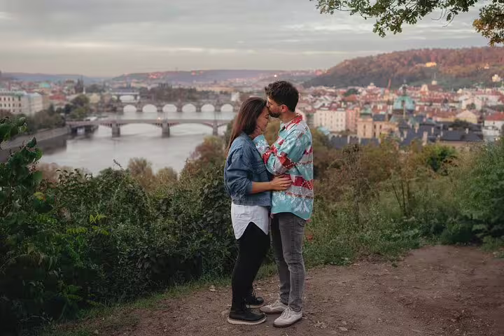 Couple embracing with panoramic view of Prague's iconic bridges and Vltava River during private photoshoot.
