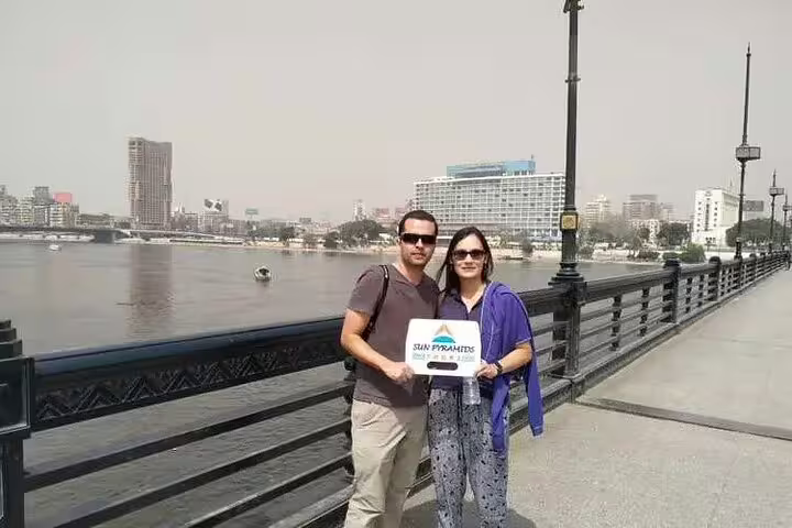 Couple on Cairo Nile Corniche before a private felucca ride, posing by the river with city skyline views
